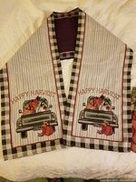 Photo showing the Happy Harvest-themed table runner with embroidered vintage truck carrying pumpkins, bordered with black and white checkered print and striped background.