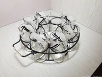 Top view of the round black iron caddy holding seven decorated glasses with black stripes