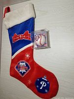 Full view of Phillies plush Christmas stocking and glass baseball ornament in plastic box.
