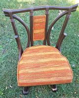 Front view of vintage swivel chair showing rust-colored striped cushioned seat and artistic wooden frame resembling tree branches.