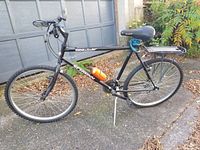 Full side view of Schwinn Sidewinder bike showing black frame, tire, seat, and cargo rack.
