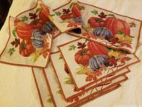 Full view of the folded table runner and four placemats with harvest themed pumpkin and autumn leaf embroidery.