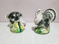 Front view of the pair of ceramic turkey salt and pepper shakers showing detailed feather painting and grass bases.