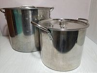 Two stainless steel stockpots, one large and one smaller, both with lids, shown side by side.
