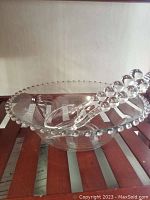Photo of the vintage clear glass salad bowl with hobnail edge and serving utensils inside.