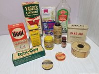 Overview of vintage salves, liniments, ointments, and bandage products displayed on a surface; includes cardboard boxes and small jars with visible brand names like Ben-Gay, Yager's, and others.