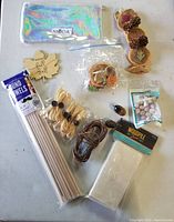 Woodcraft items including wooden plaques, wood dowels, small wood balls and shapes, packaged wood pips, and small decorative elements arranged neatly on a white background.