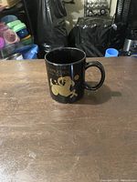 Black mug with gold Capricorn zodiac design on one side.