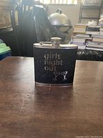 Front view of black glitter flask with silver text 'girls night out' and cocktail glass graphics.