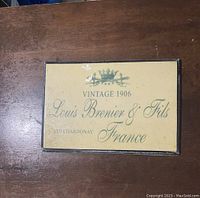 Front view of framed vintage French wall decor with text and emblem on display.