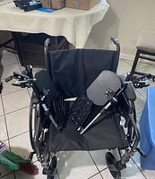 Front view of black manual wheelchair showing fabric seat and adjustable leg rests with padded supports.