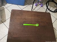 Green long feeding spoon placed on a wooden table.