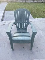 Front view of green plastic lawn chair showing seat, armrests, and slatted backrest