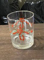 Clear cocktail glass with red and green holiday ribbon design on a wooden surface.