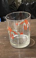 Side view of the cocktail glass showing the red flower and ribbon design on clear glass.
