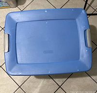 Top view of the closed blue plastic storage bin with grey handles showing the lid surface and markings.