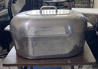 Large stainless steel roasting pan with lid on top showing overall shape and size