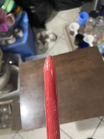 Side view of the red tall candle showing length and wax texture with some surface wear.