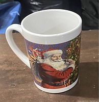 White ceramic mug angled to show the Santa Claus illustration on the side.