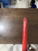 Close-up top angle showing tip of tall red taper candle with some surface wear.