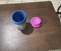 Photo of the open sippy cup showing blue interior and pink lid on wooden surface