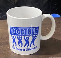 Side view of white ceramic mug showing blue 'TOGETHER' text above four human figures holding up the word and the phrase 'We Make A Difference' below.