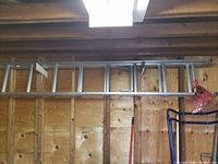 Side view of aluminum extension ladder mounted on wooden wall.