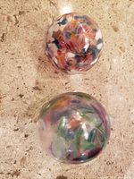 Two glass witch balls placed on a stone surface, showing colorful swirl patterns inside each ball from top view.