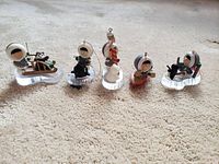 Full view of all five Hallmark Eskimo ornaments arranged in a line on carpet showing detailed characters and bases.