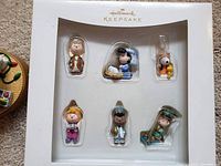 Hallmark Keepsake packaging with 6 small Charlie Brown Christmas character ornaments including Charlie Brown, Lucy, Snoopy, Sally, Franklin, and Linus