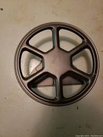 Top view of black circular hose rack with multiple spokes designed for holding garden hose.