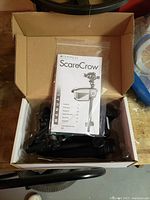 Box containing the unassembled motion detection sprinkler unit and stake, with manual on top.