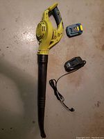 Top view of cordless leaf blower with battery and charger on stained floor