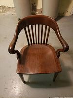 Front view of the solid wood vintage office chair showing curved armrests and slat backrest.