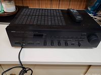 Front angled view of Yamaha stereo amplifier showing front controls and power cable.