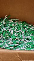 Box filled with many green Expo dry erase markers capped, scattered randomly.