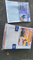 Two boxes of Filtrete filters lying on the ground, showing front packaging of Advanced Allergen and Micro Particle Reduction types.