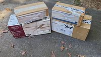 Four cardboard boxes of ceiling fans photographed outdoors on pavement.