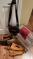 View of the purses: brown, tan, red; two metal stands; three curved wall décor pieces