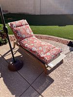Side view of the chaise lounge chair showing the aluminum frame and floral reversible cushion.