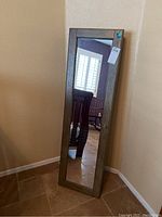 Front view of tall wood-framed jewelry cabinet with full-length mirror door, showing overall size and condition.