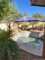 Outdoor cantilever patio umbrella installed near pool, fully extended to show size and shape