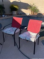 Four metal frame patio chairs with red nylon/polyester back and seat fabric and patterned seat cushions, shown outside near a pool.