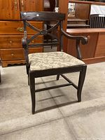 Front view of the antique parlour chair showing wooden carved back and cushioned seat.