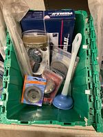 Overview of bin containing all plumbing and hardware items including faucet box, plunger, safety bar, showerheads, and strainers