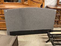 Gray fabric headboard with a black base, front view showing shape and condition.