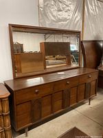 Front view of wooden dresser with attached rectangular mirror, showing drawer configuration and wood tone.