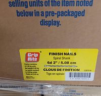 Close-up photo of a label on a cardboard box showing specific product details: Grip-Rite finish nails, spiral shank, 6d size, 2 inch length, net weight 9 kg, box contains 20 pre-packaged units.