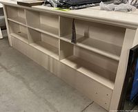 Photo of the large king bookcase headboard showing its length, shelving compartments, and finish condition.