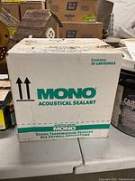 Photo of closed white box containing 30 cartridges of Mono Acoustical Sealant with branding and product details visible.